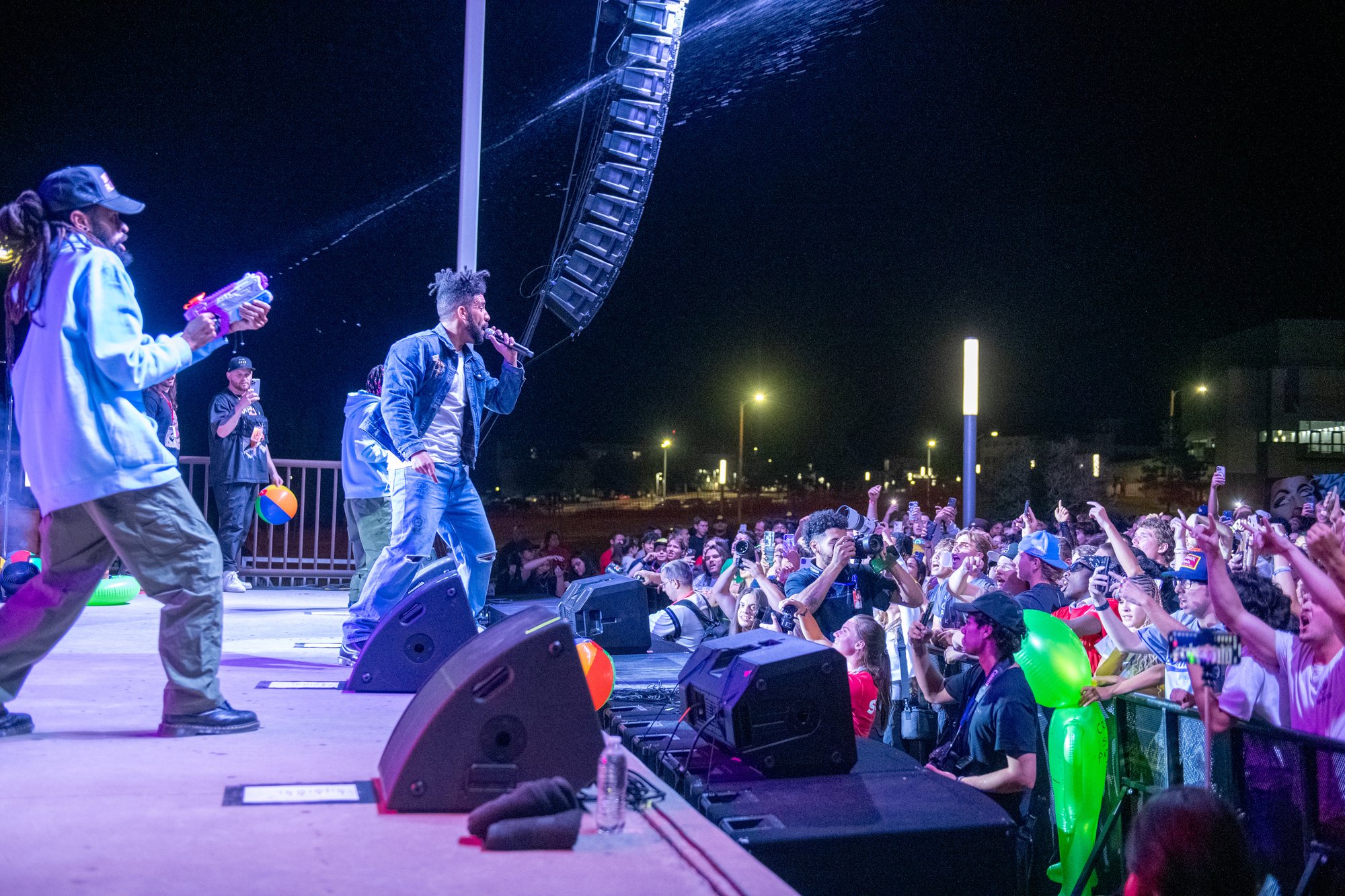 A lively performance at PACKFEST 2024 at CSU Pueblo, featuring performers on stage engaging with an energetic crowd under bright lights in an outdoor setting.