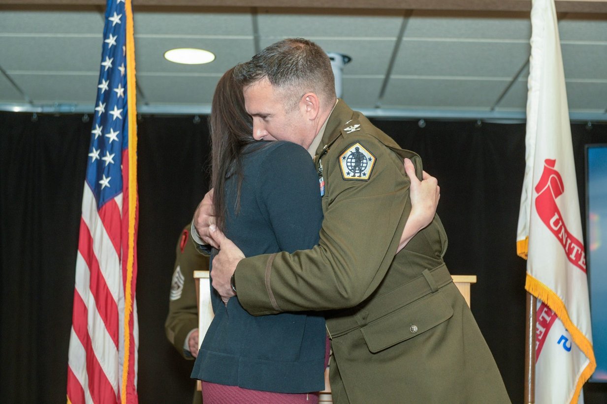 A promotion ceremony embrace beneath the colors, Perfectionshoots military and veteran event photography