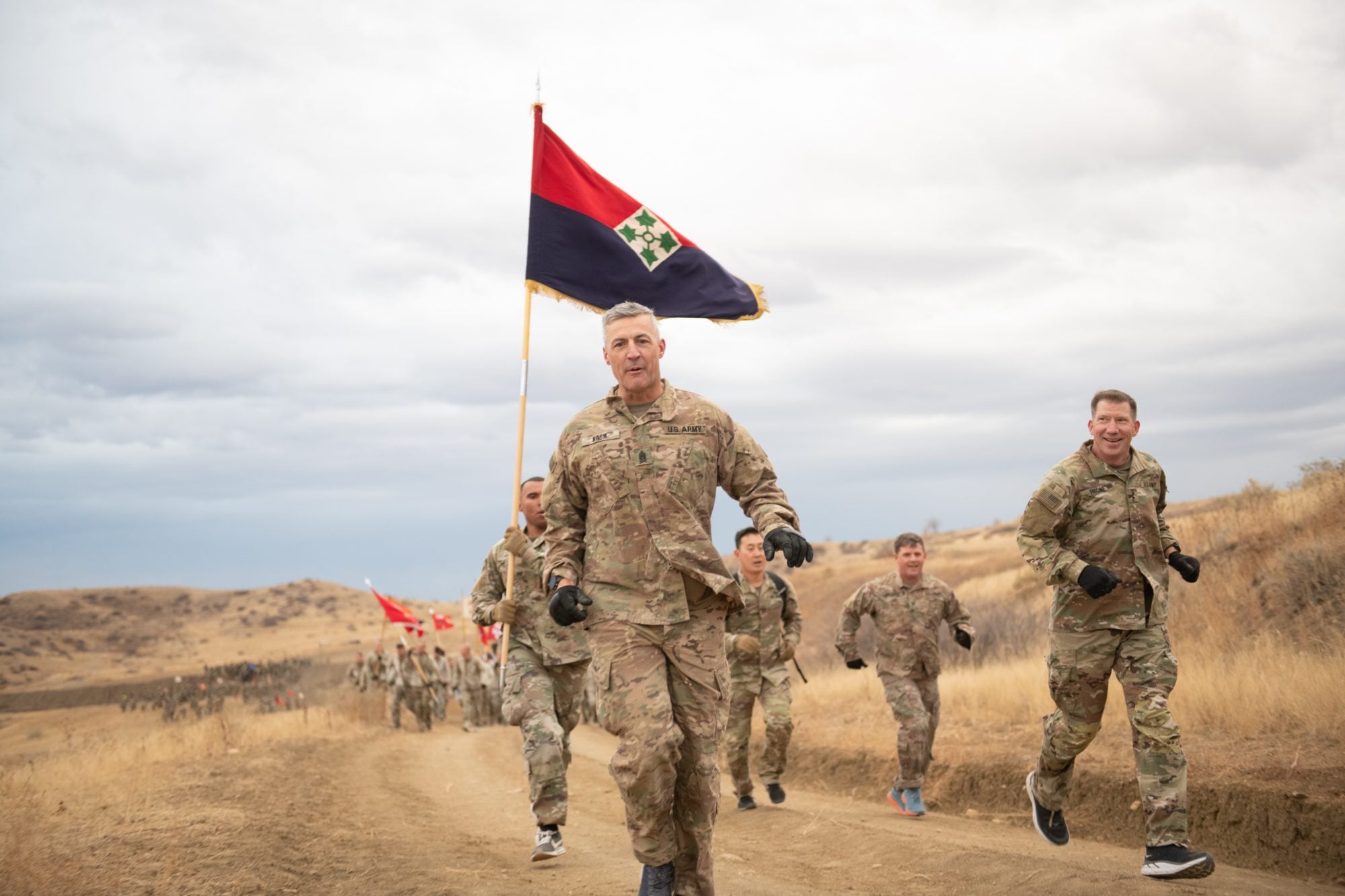 The division commander and division command sergeant major lead their soldiers on a division run beneath the colors, documented by Perfectionshoots